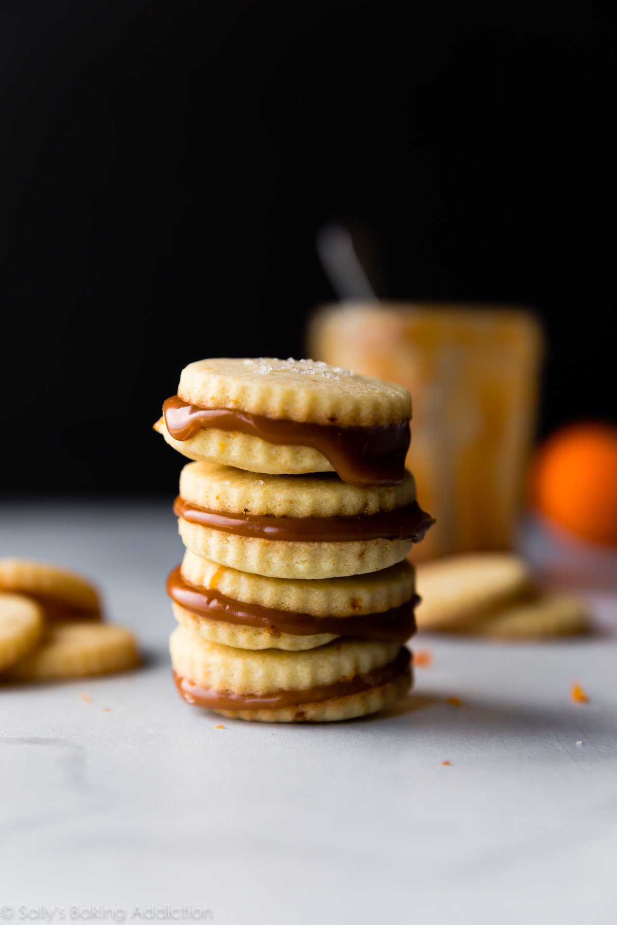 Mouchetés de zeste d'orange et fourrés au caramel, ces sandwichs aux biscuits sablés sont à la fois simples et sophistiqués! Recette sur sallysbakingaddiction.com