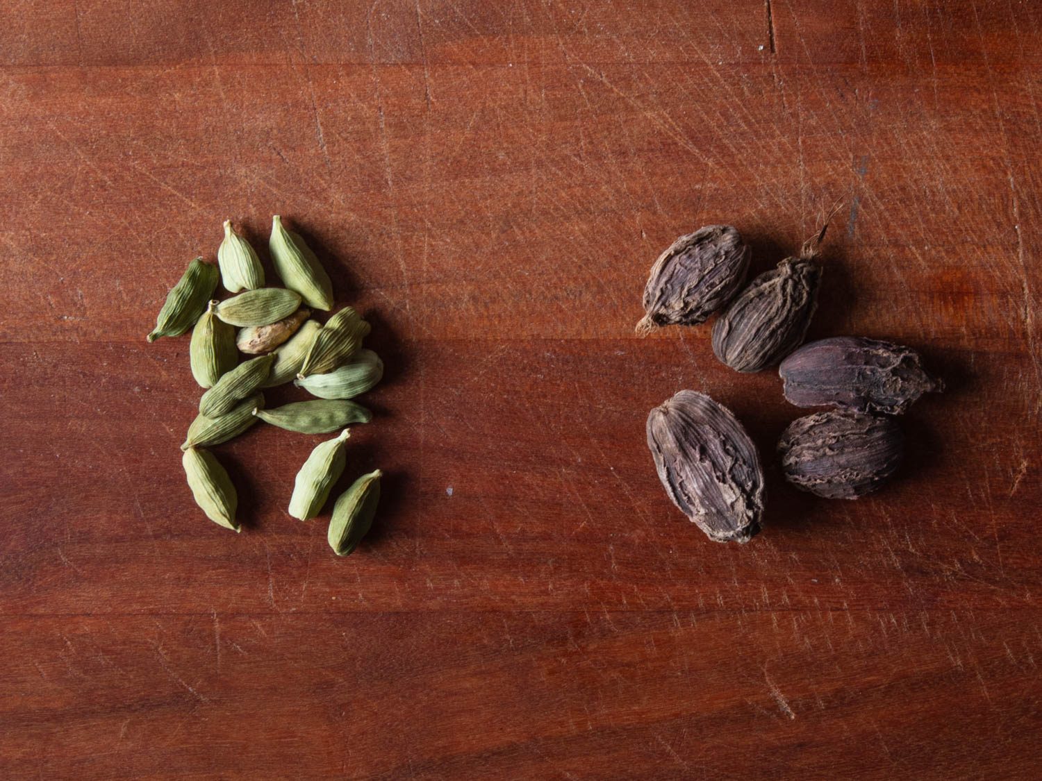 Comparaison côte à côte des gousses de cardamome verte (à gauche) et des gousses de cardamome brune (à droite)