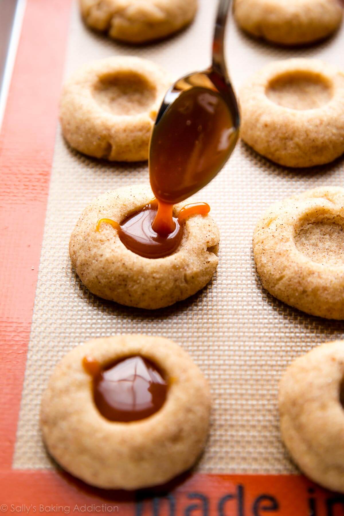Biscuits à l'empreinte de pomme aux épices remplis de caramel fait maison! Ces délicieux biscuits d'automne sont complètement irrésistibles et si simples à préparer! Recette sur sallysbakingaddiction.com