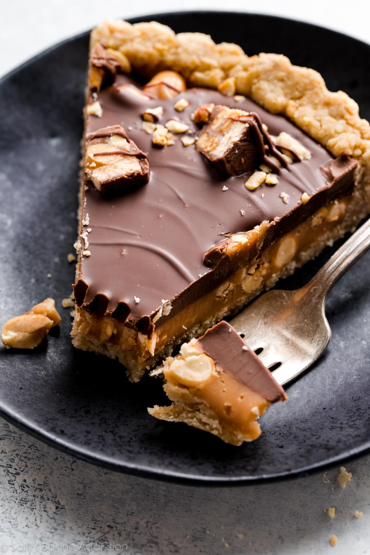 Tarte au caramel Snickers avec caramel salé, croûte d'arachide, arachides salées et garniture au beurre d'arachide au chocolat! Recette sur sallysbakingaddiction.com