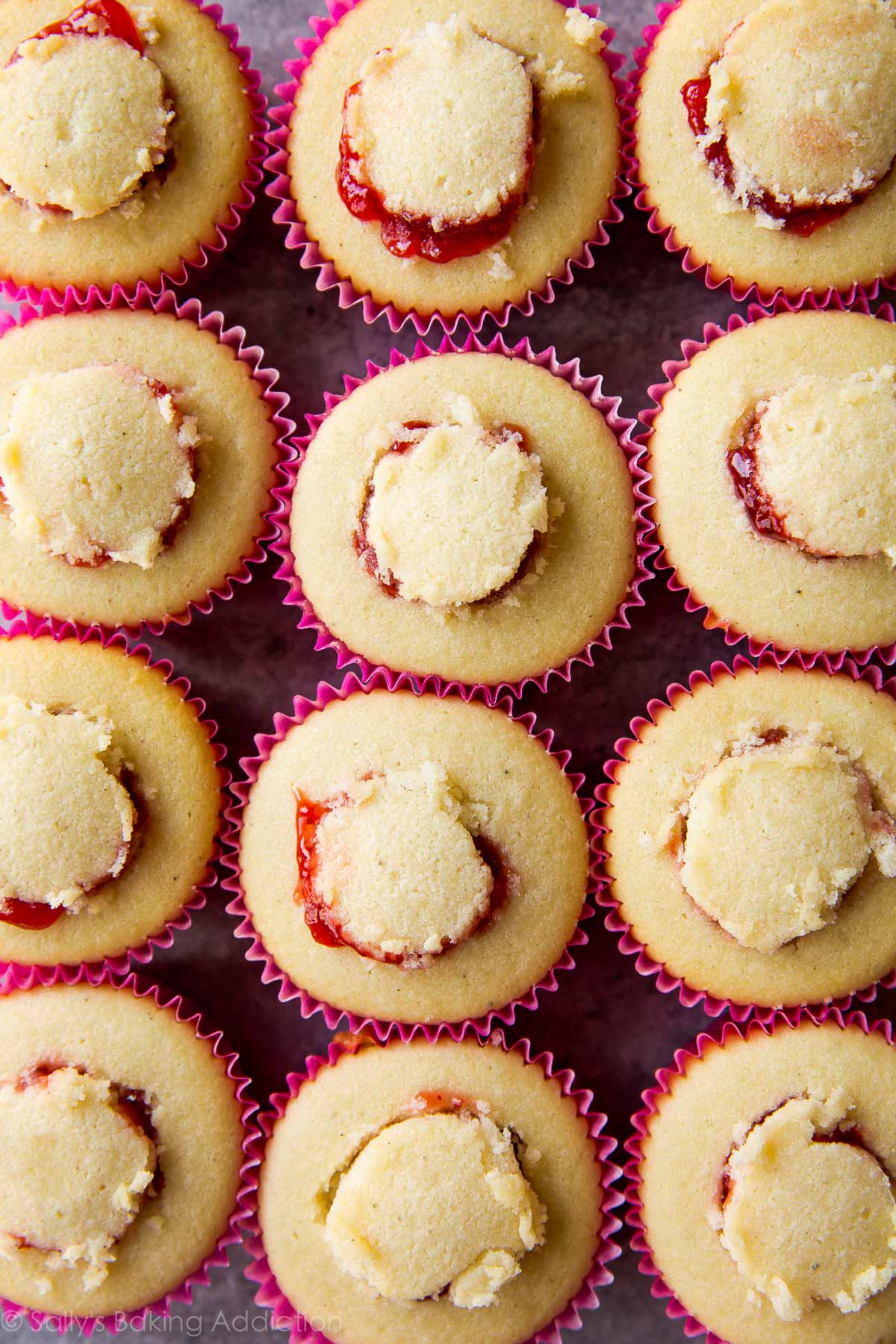 Cupcakes à la vanille moelleux et moelleux garnis de glaçage au beurre d'arachide et remplis de votre gelée préférée! Recette sur sallysbakingaddiction.com