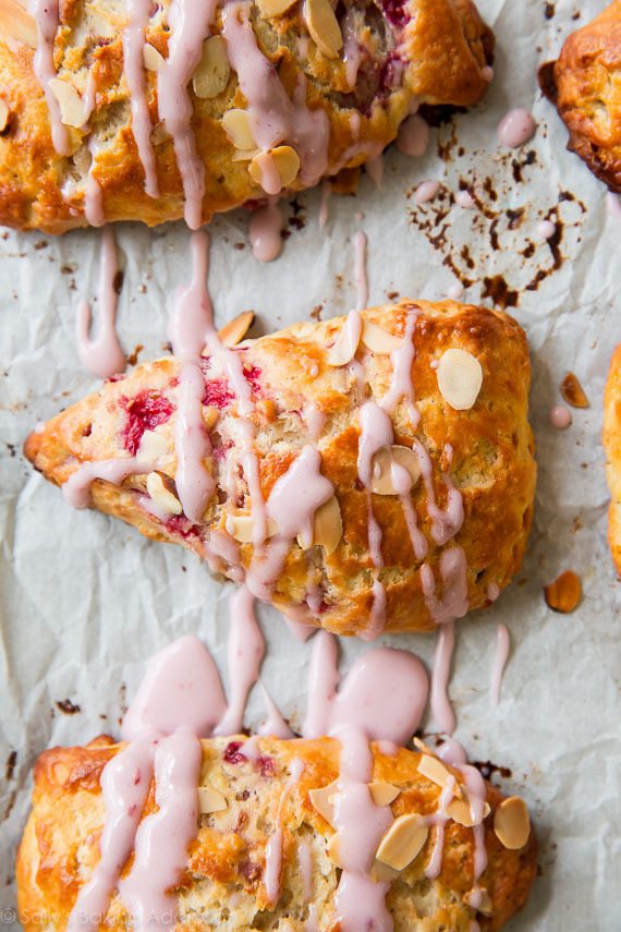 Scones feuilletés, doux et tendres avec des framboises juteuses et une saveur d'amande à chaque bouchée. Prenez tous mes conseils de cuisson au scone et la recette sur sallysbakingaddiction.com