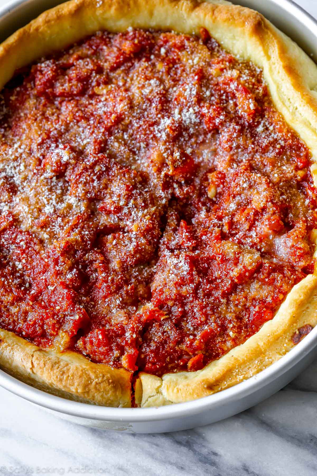 Voici comment préparer une pizza au plat profond de Chicago au goût authentique. Compléter avec la croûte au beurre, la sauce tomate légèrement sucrée et une épaisse couche de fromage. Recette sur sallysbakingaddiction.com