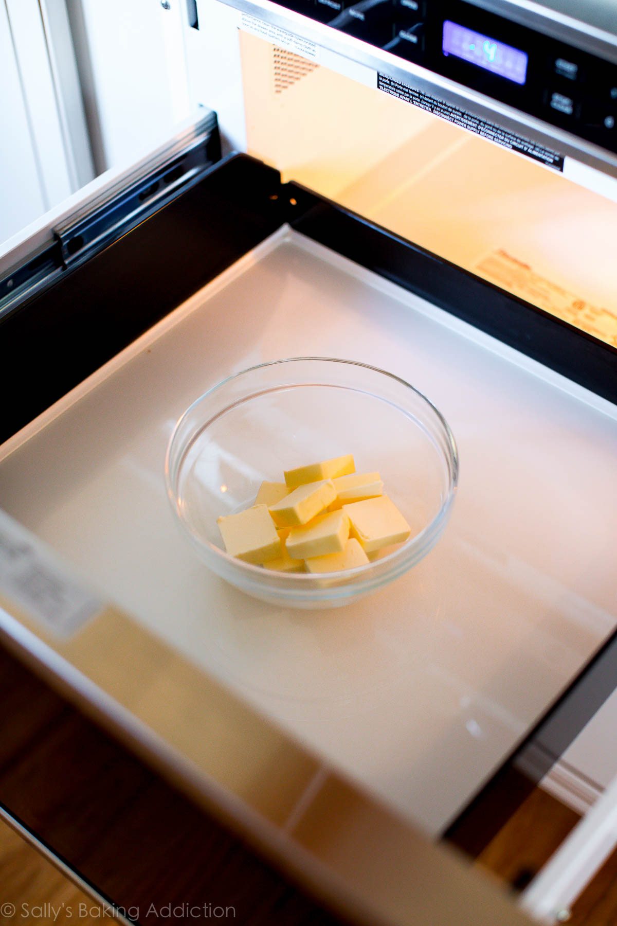 Bol en verre avec du beurre à l'intérieur sur un micro-ondes à tiroir ouvert