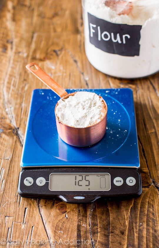 une tasse à mesurer avec de la farine sur une balance de cuisine