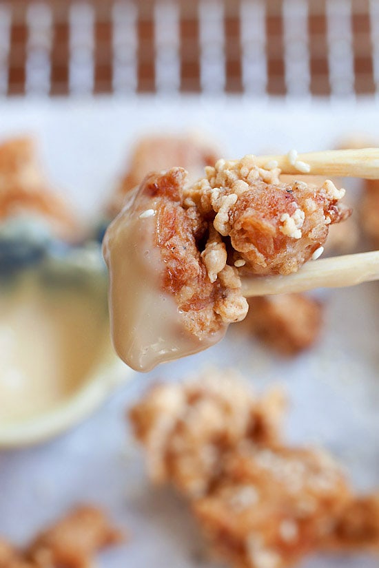 Un morceau de poulet frit japonais croustillant et croquant cueilli avec une paire de baguettes trempées dans une sauce mayo miso.