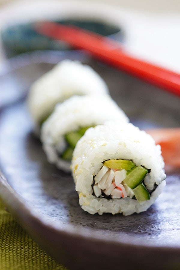 California roll sushi ou California maki roll, prêt à servir avec une paire de baguettes japonaises rouges.