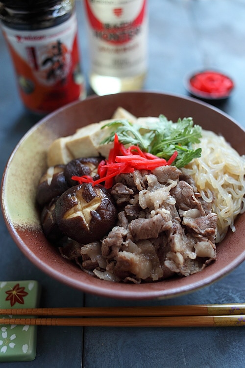 Bol de riz donburi sukiyaki japonais fermé garni de tranches de bœuf, de champignons shitake, de tofu et de nouilles shirataki.