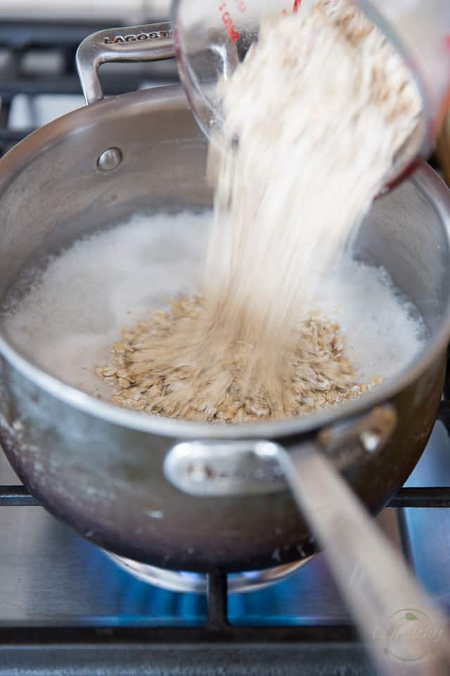 Des flocons d'avoine sont ajoutés à une casserole contenant du lait bouillant et de l'eau de coco