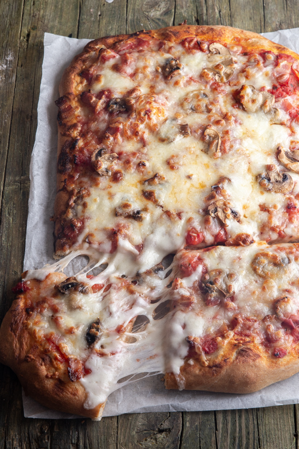 pizza sur papier sulfurisé avec une tranche coupée.