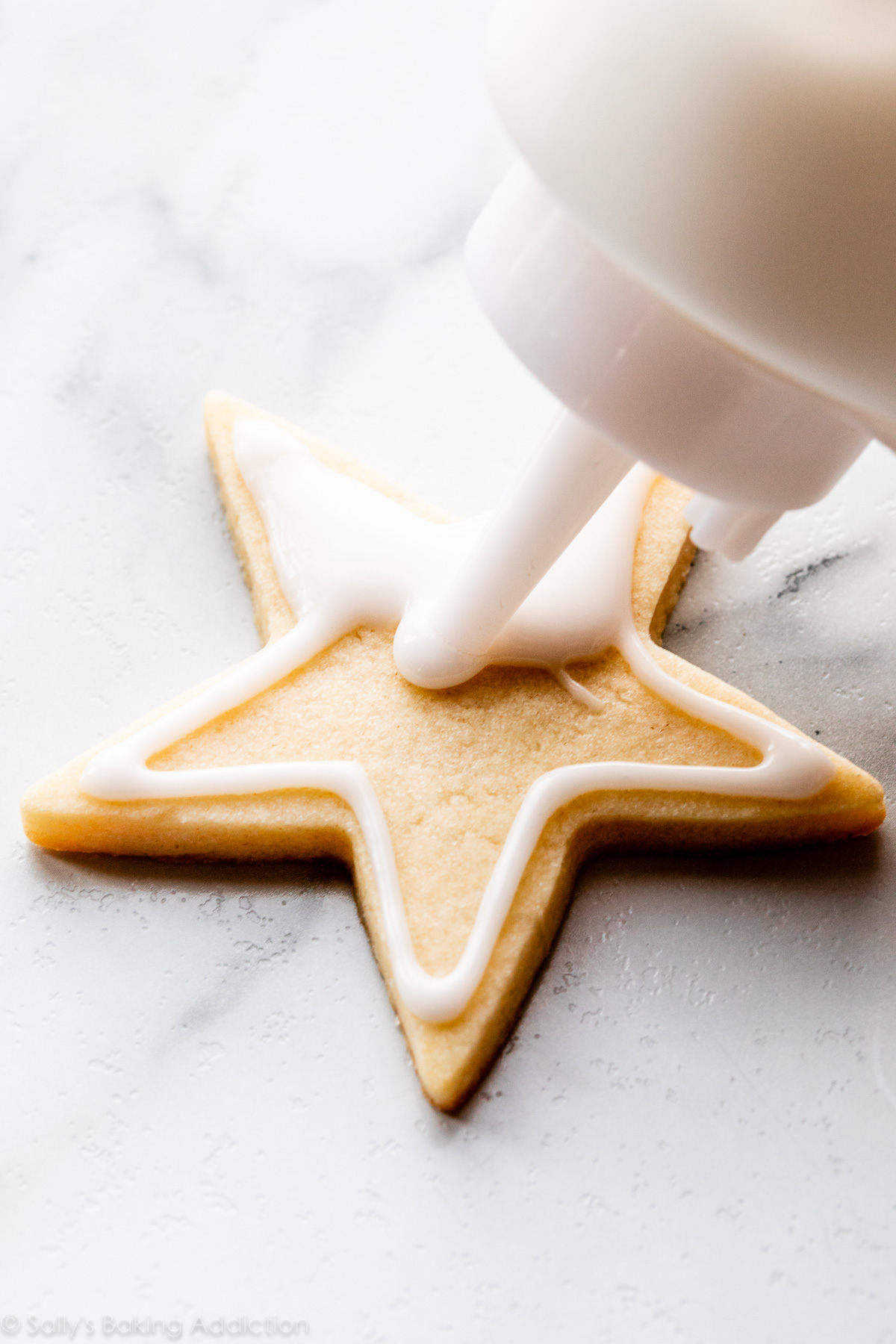décorer un biscuit au sucre avec un glaçage blanc à l'aide d'une bouteille souple