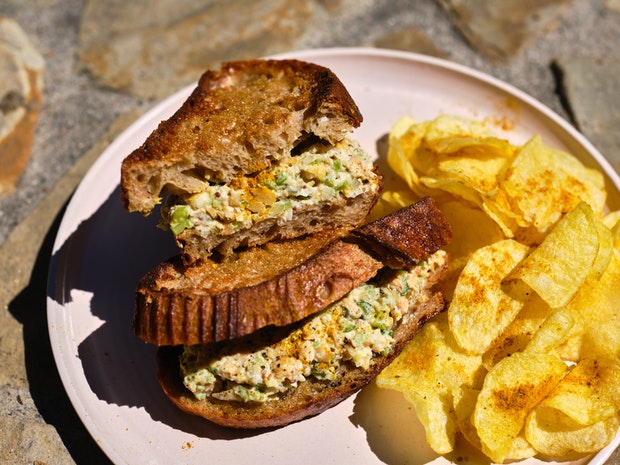 Photo en gros plan d'un sandwich à la salade de pois chiches sur une assiette coupée en deux sur une assiette avec des croustilles
