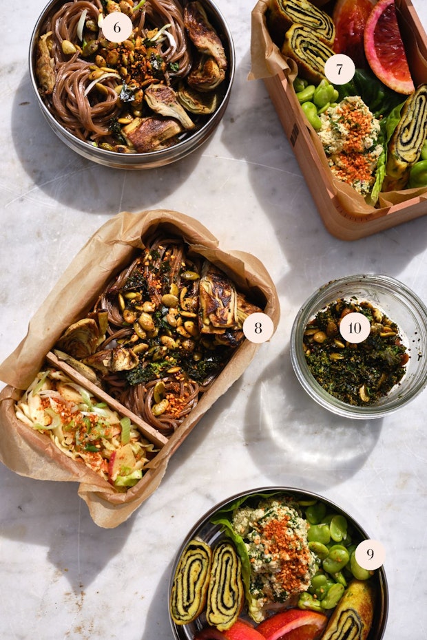 Un assortiment d'idées de déjeuner disposées sur une table comprenant des nouilles soba, du tamagoyaki, de la salade de chou et des graines épicées