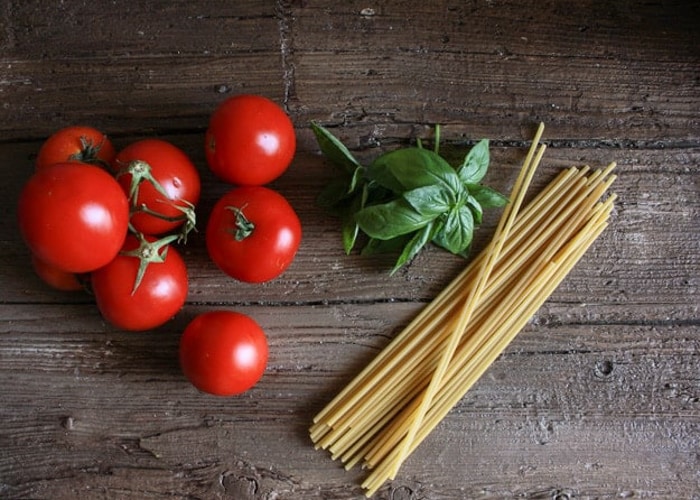 tomates, basilic et pâtes sur une planche.
