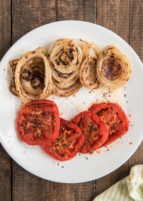 L'oignon et les tomates cuits sur une plaque blanche.